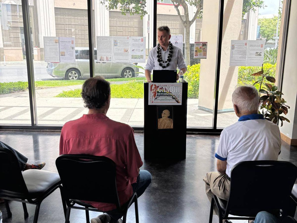 International Peace Educator and Mediator Paul Dziatkowiec addresses the audience at the podium during his lecture in Honolulu on August 5, 2026.